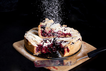 Baked American сherry pie with powdered sugar in the kitchen at home
