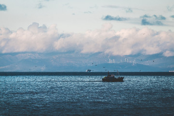 Fishing boat in the sea, under beautiful clouds, Spain's coast in the background (Strait of Gibraltar)