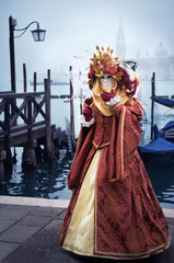 Woman in Venetian carnival outfit in lagoon