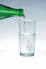 Mineral water pours from the bottle into the glass