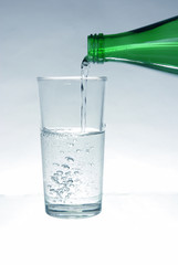 Mineral water pours from the bottle into the glass
