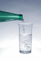 Mineral water pours from the bottle into the glass