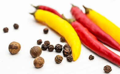 Small chilli peppers and pepper peas on white wooden table.