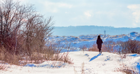 The girl walks in the winter in nature. Winter sunny day. Lonely woman in the nature_