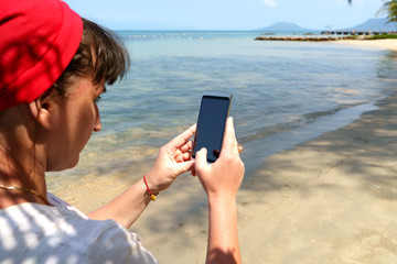 hipster girl using phone on the beach