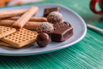 Shortbread cookies and chocolates on a btruzy plate, standing on a green wooden background.