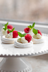 Mini Pavlova meringue with whipped cream and raspberries.