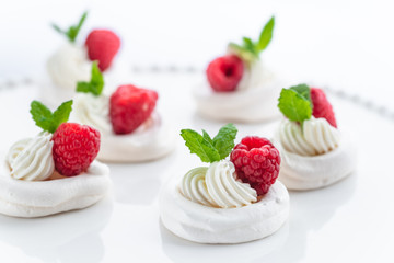 Mini Pavlova meringue with whipped cream and raspberries.