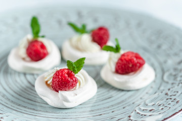 Mini Pavlova meringue with whipped cream and raspberries.
