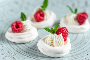 Mini Pavlova meringue with whipped cream and raspberries.