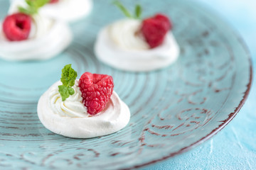Mini Pavlova meringue with whipped cream and raspberries.