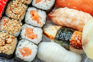 Multicolored rolls and sushi rice, caviar and salmon, eel, trout on the table in the background