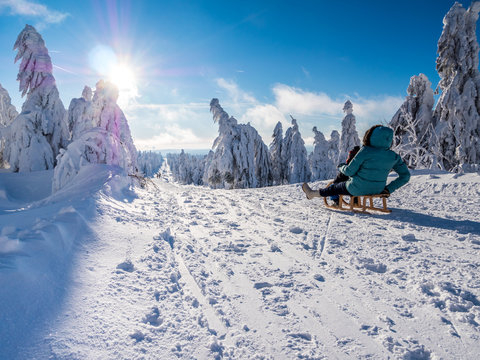 Happy children sledding in snowy German erzgebirge mountains during winter vacation