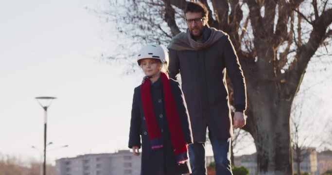 Daughter child girl learning segway riding with dad teaching in city.Modern future transport technology.Active safety family.Sidewalk urban outdoor.Warm sunset cold backlight.4k slow motion 60p video