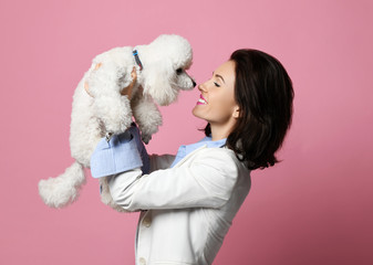 Beautiful woman hugging her lovely white poodle dog puppy on pink happy smiling