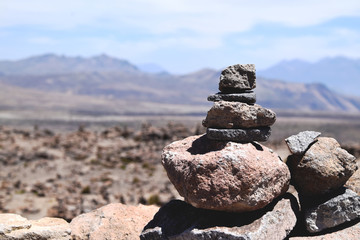 Rocks piled on top of each other with the mountains in the background. Photo taken in Peru.