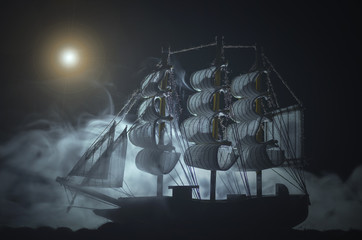 Pirate ghost ship in a night smoky sea background.