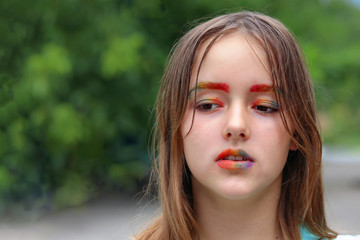 Fototapeta premium close up portrait of preteen girl with rainbow make up, colorful brows, lips and eyelids. Child creativity. Tribal girl. Artistic self-expression. Teenager protest.