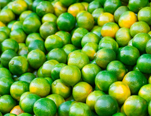 Close up fresh green mandarins in market. It can be used as a food background (selective focus)