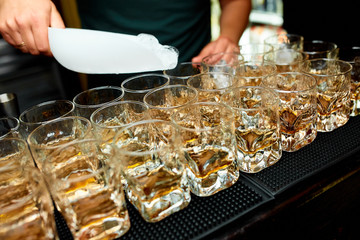 Many alcoholic cocktails whiskey with ice and lemon in glasses 