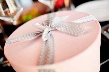 Round pink gift box with a speckled bow on the wedding table