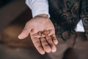 groom's hand holds wedding rings. soft focus
