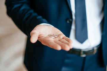 Fototapeta premium groom's hand holds wedding rings. soft focus