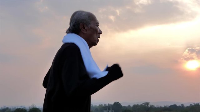 Senior Asian male jogging in the evening on the road. Living healthy lifestyle with exercise. Slow Motion