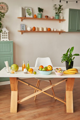 Fruits: apples, watermelon, pineapple, bananas, lemons, oranges o table, warm loft-style kitchen. Plate of ripe fruits on table. Home modern kitchen table top decorated with summer exotic fruits 