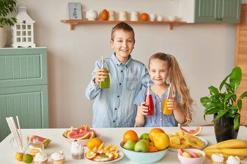 Children eat fruit pineapple, watermelon, apples and drink drinks with chia. Healthy food in the children's menu. Happy children with fruits and fresh juice in kitchen, kids healthy eating concept 