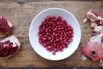 sliced pomegranate, pomegranate fruits in a white plate on a wooden dark background