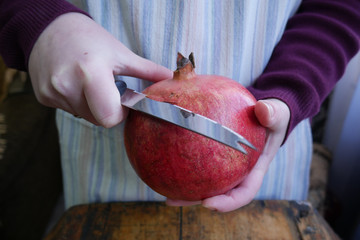 man cuts a ripe pomegranate with a knif 