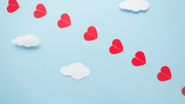 Happy Valentines day. Eco wooden children's plane on a blue background with red heart, and garland in the shape of a heart white clouds, flags. Stop motion animation loop.