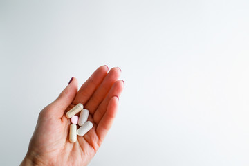 The girl holds in her hand pills, vitamins, drugs on a white background. Stretched hand with a handful of pills on white background