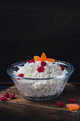 cottage cheese in a bowl with dried fruits on a dark background