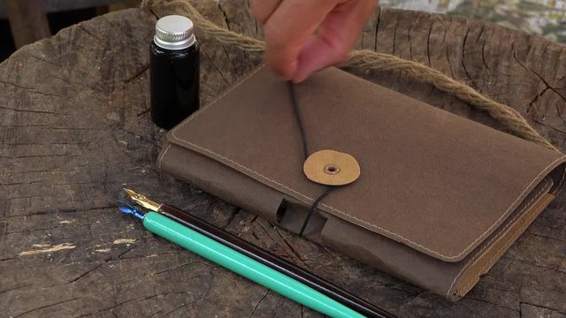 Using hand to open an agenda with thread, wood vintage fountan pen and ink pot bottle&nbsp;