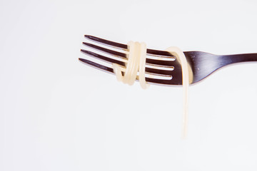 A single cooked spaghetti on a fork