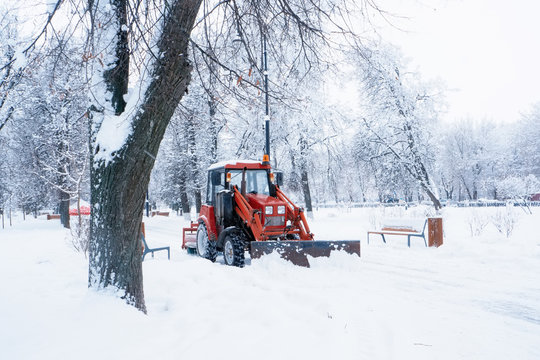 A red bulldozer cleans the streets after heavy natural snowfall. Getting ready for Christmas. Freezing day