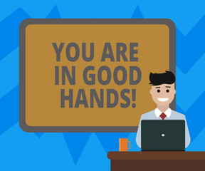 Text sign showing You Are In Good Hands. Conceptual photo Best service offering reliable professional assistance Blank Bordered Board behind Man Sitting Smiling with Laptop Mug on Desk