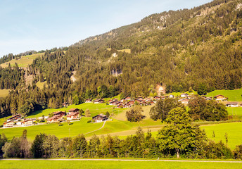Mountains of the Swiss Alps with wooden huts and meadows on a sunny day.