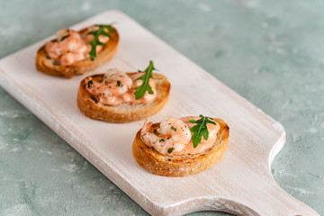 Bruschetta sandwiches with shrimps, creamy sauce and rocket salad.