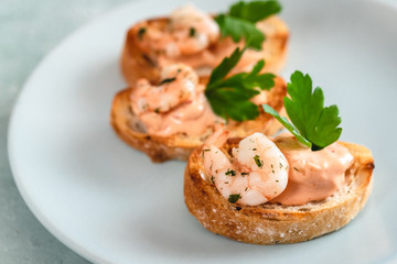 Bruschetta sandwiches with shrimps, creamy sauce and parsley.