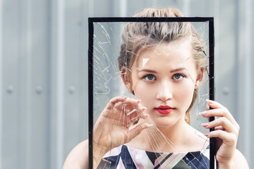 Beautiful teen girl holding broken glass in her hands. concept feminism.