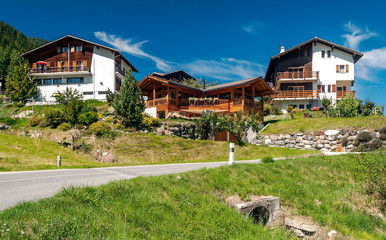 Wooden houses in the meadows of the Swiss Alps in the Saint Luc valley on a sunny day.