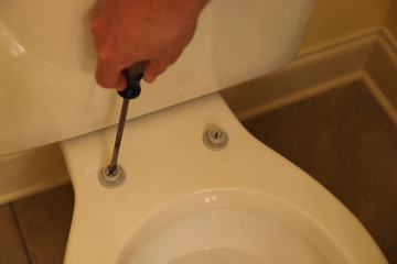 Plumber repairing broken toilet seat