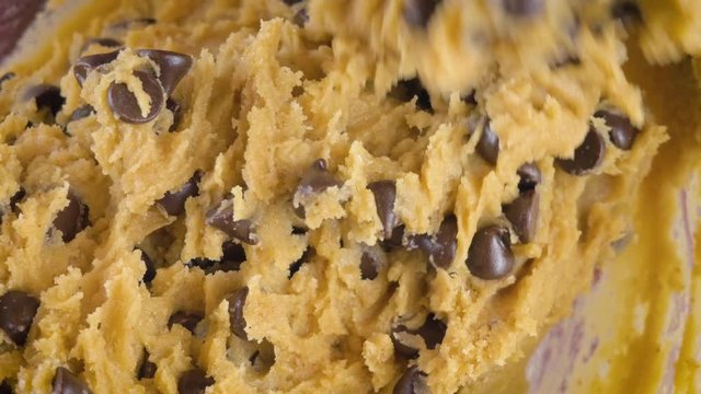 Closeup stirring chocolate chips into raw cookie dough in 4k. Top view can be used for step by step gif recipes for cooking shows, salmonella outbreaks and unhealthy diets from refined sugar. 