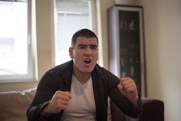 Young adult man watching football on television: Goal