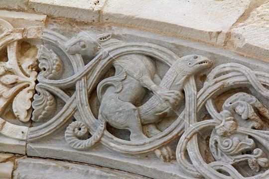 belva che cattura un pesce; rilievo sull'arco del portale maggiore della Cattedrale di Trani (Puglie)