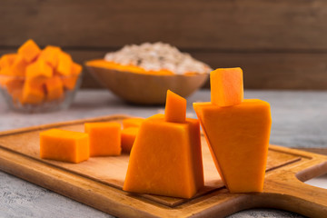 Figures of a man and a woman carved from a pumpkin. The concept of relationships between people. Cubes of sliced ​​ripe pumpkin.