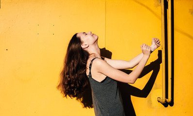 Girl dancing in front of a yellow wall